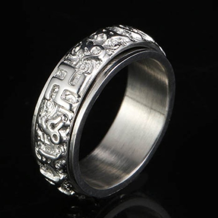 Silver-tone titanium spinner ring with raised six-word mantra symbols against a glossy black background