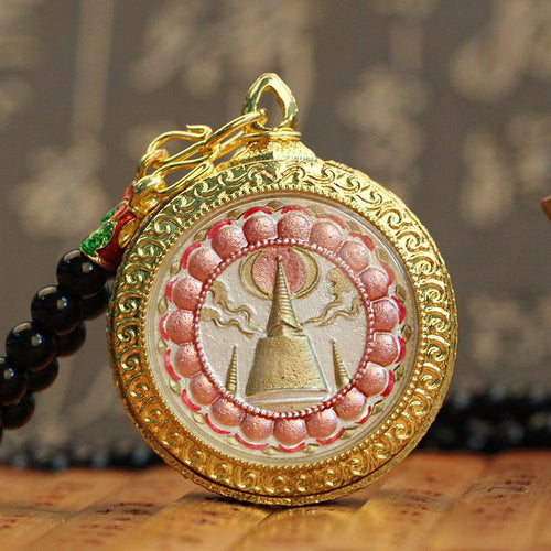 Back of round Thai Buddha amulet showing a gold stupa within a pink lotus border