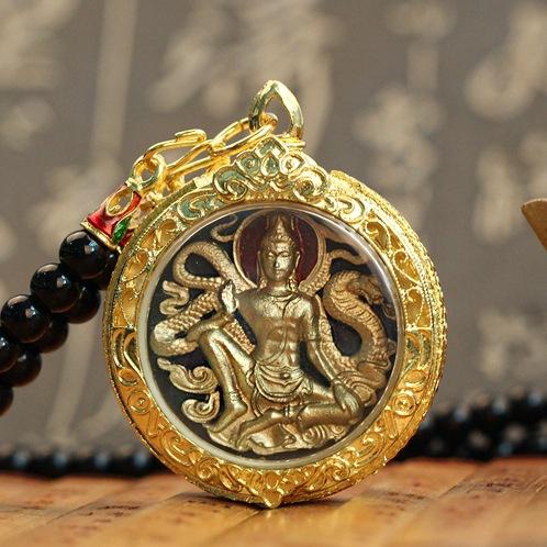 Round Thai Buddha pendant with raised gold seated figure in an ornate gold frame