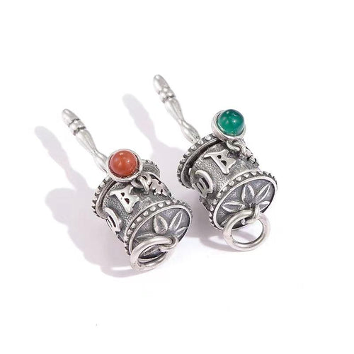 Two silver prayer wheel charms with red and green bead accents displayed together