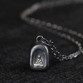 Vintage 925 silver arched Buddha pendant necklace resting on dark textured surface